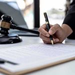 Migrant Maniac Kills 3 in Psychotic Rage Hand signing legal document beside gavel and laptop