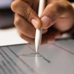 Hand signing a digital document with a stylus on a tablet