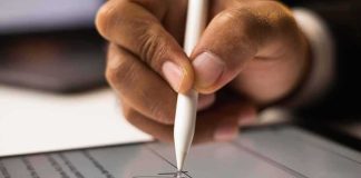 Hand signing a digital document with a stylus on a tablet