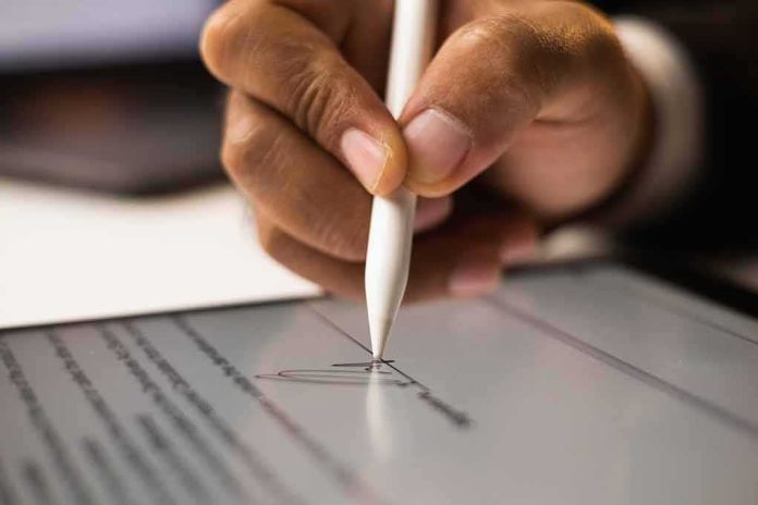 Hand signing a digital document with a stylus on a tablet