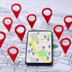 Smartphone with map app surrounded by red location pins