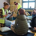Volunteers assist people resting on mats in a temporary shelter