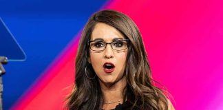 Woman with glasses speaking on stage with colorful backdrop