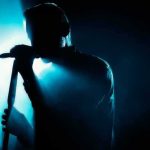 Singer silhouette holding a microphone on a dark stage