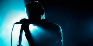 Singer silhouette holding a microphone on a dark stage