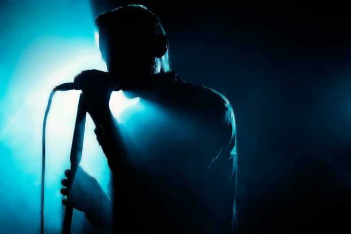 shutterstock_472862491 Singer silhouette holding a microphone on a dark stage