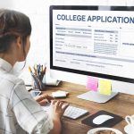 Student completing a college application on a desktop computer