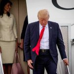 Air Force One Snub Sparks Media Fury man in suit with red tie walking down airplane stairs