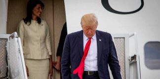 Air Force One Snub Sparks Media Fury man in suit with red tie walking down airplane stairs