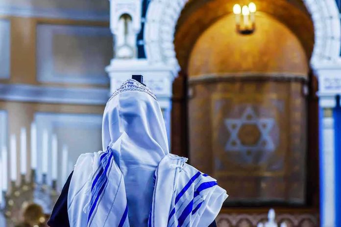 shutterstock_709900843 Person in white and blue prayer shawl facing ornate interior