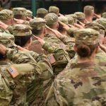 Soldiers in camouflage uniforms salute in formation