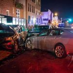 two cars collide on a city street at night