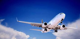 Commercial airplane flying with landing gear extended against a blue sky