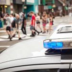 Trans Sex Workers CLASH With City Police police car roof light bar with blue lights near a busy crosswalk