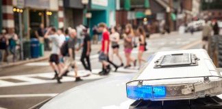 Trans Sex Workers CLASH With City Police police car roof light bar with blue lights near a busy crosswalk