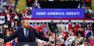 Trump Vows to Return Stolen Dem Money Back to Americans! Crowd at a political rally with a speaker at a podium; Stephen Paea, Curtis Lofton, Walter Jones, John Sullivan, and Colin David Jones present