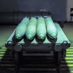 Green missiles on a wheeled cart in an industrial bay