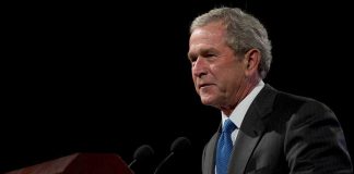George W. Bush speaking at a podium with microphones
