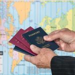 El-Sayed Admits He Carries Dual Citizenship! Hands holding multiple passports in front of a world map